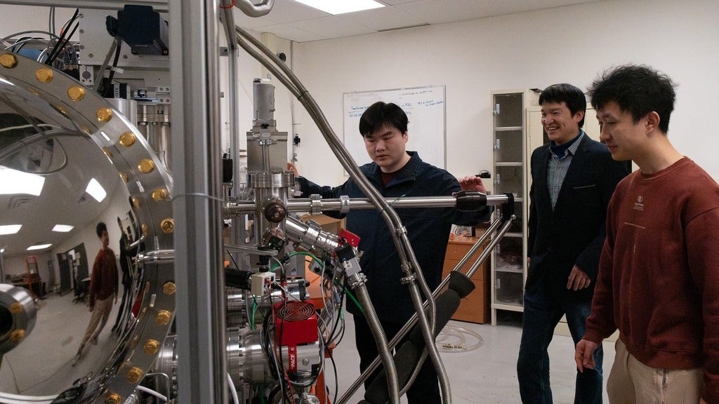 Three men standing in front of large scientific instrument