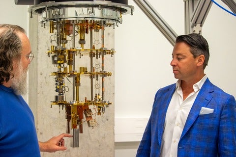 Chris Wilson and Eugene Profis looking at a quantum computer, gold plated hardware that processes quantum information 
