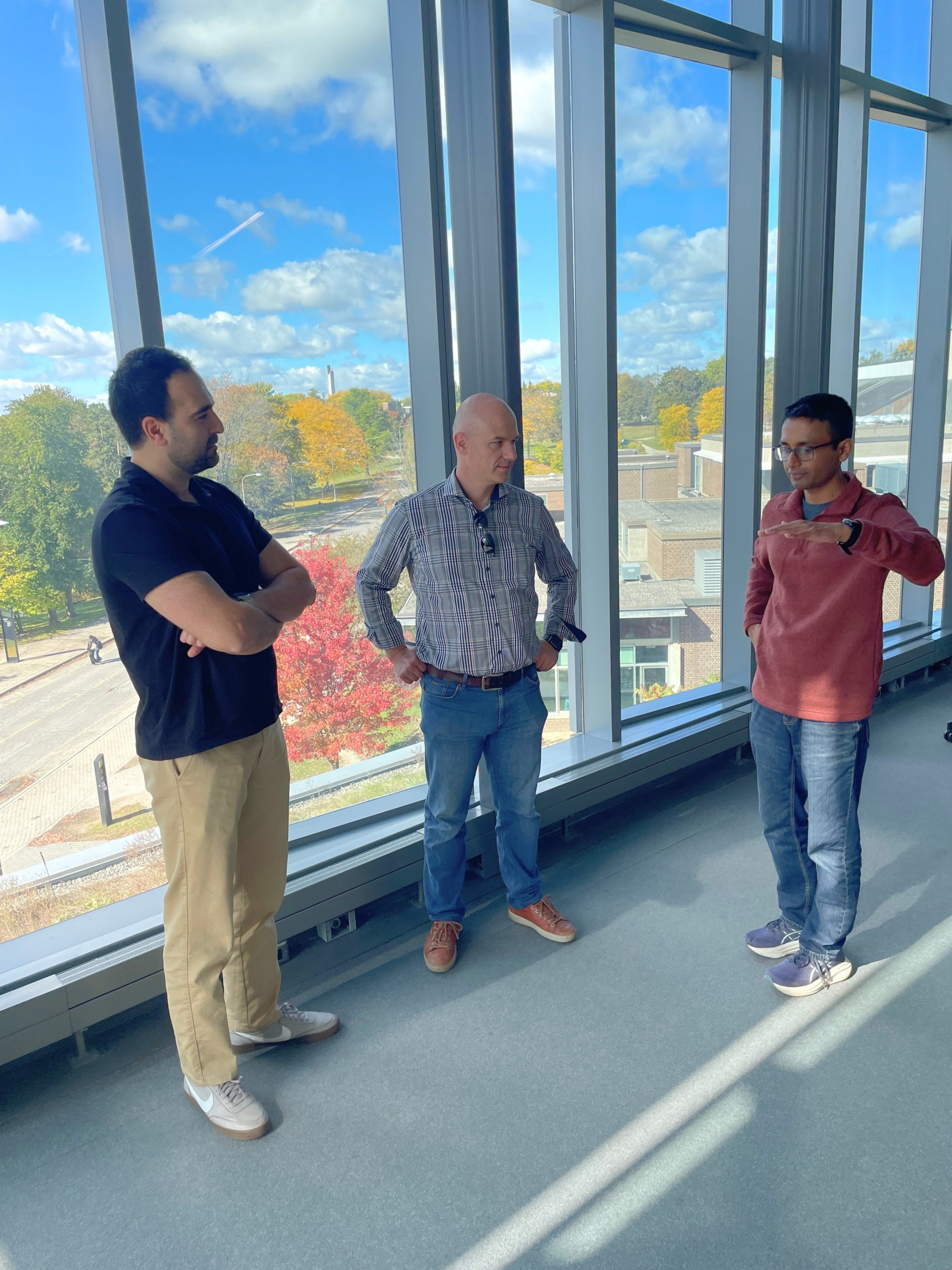 Abdolereza, Michal and Shrees standing in front of a window