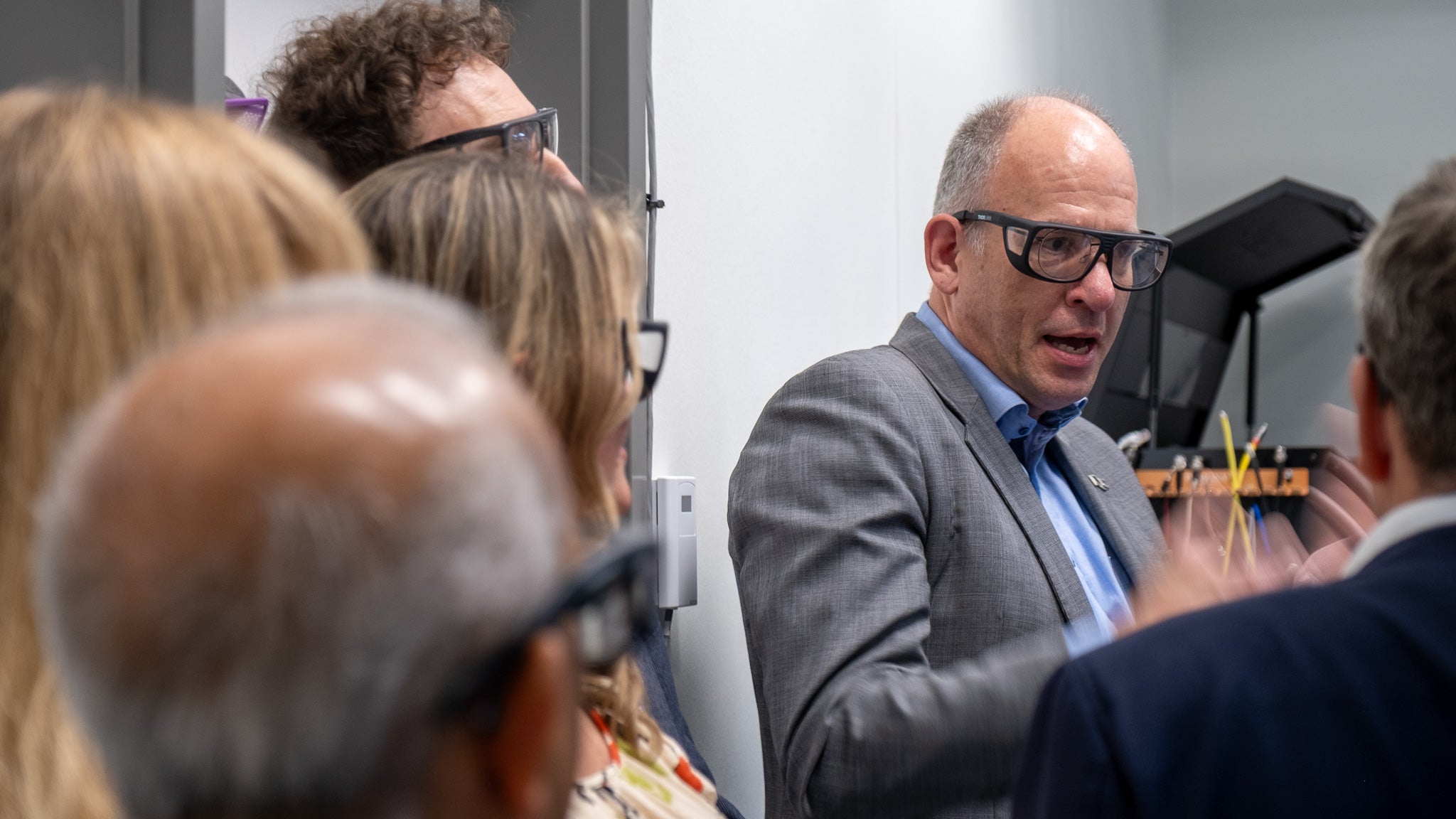 Man talking wearing protective glasses and five people looking at him