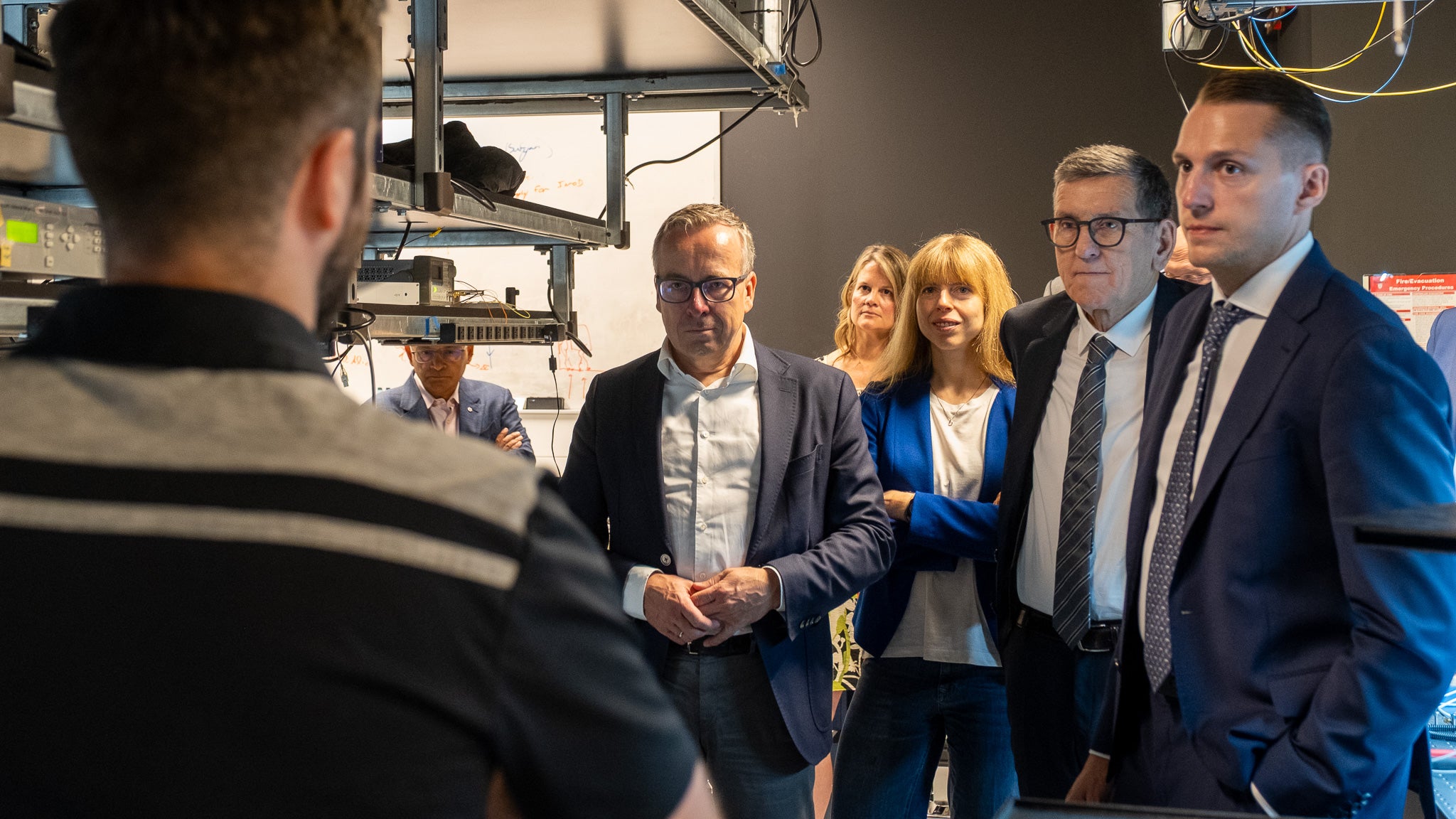 three men and two women watching a man while listening to him