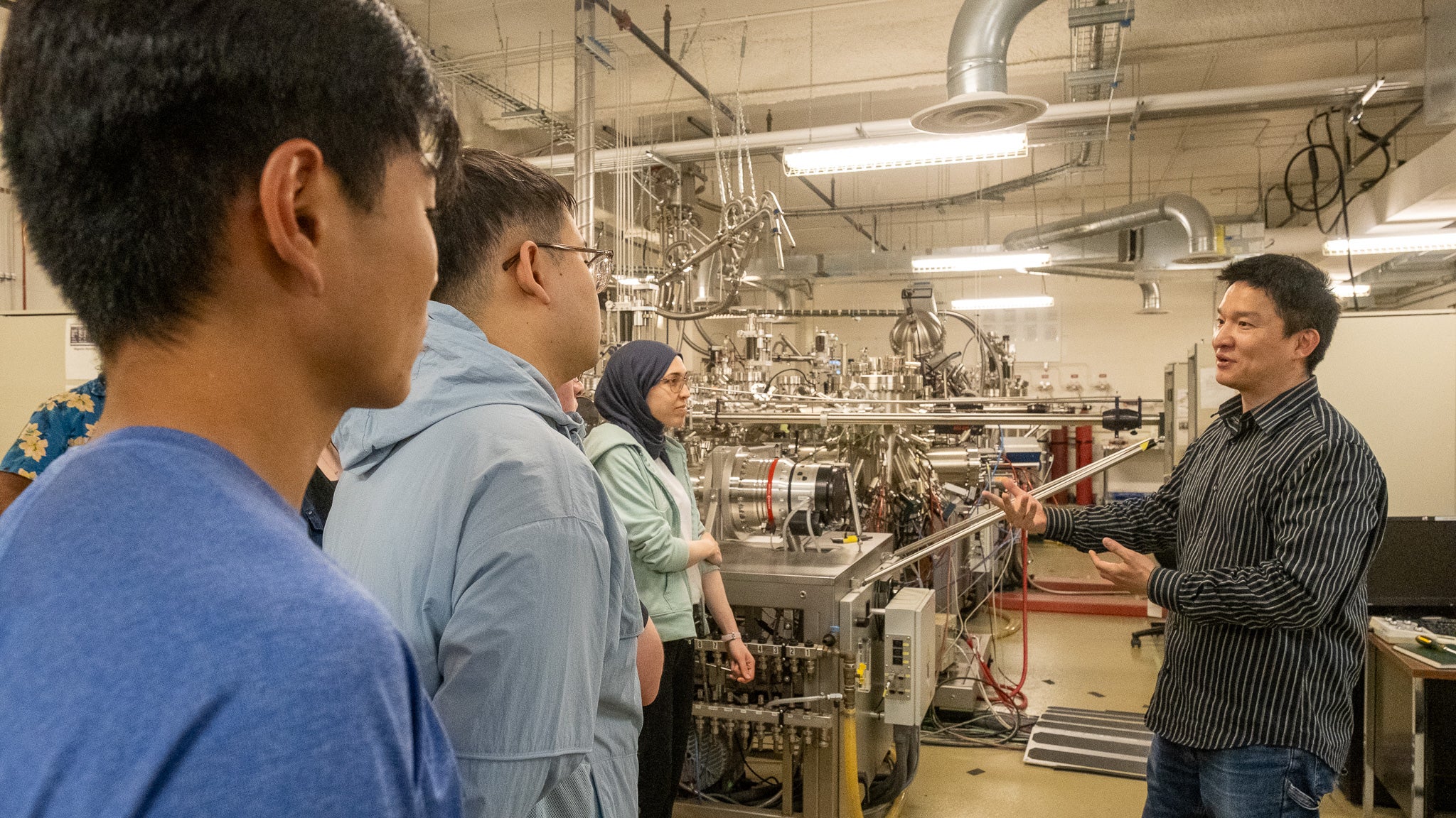 A man speaks to a group of young students in a quantum lab