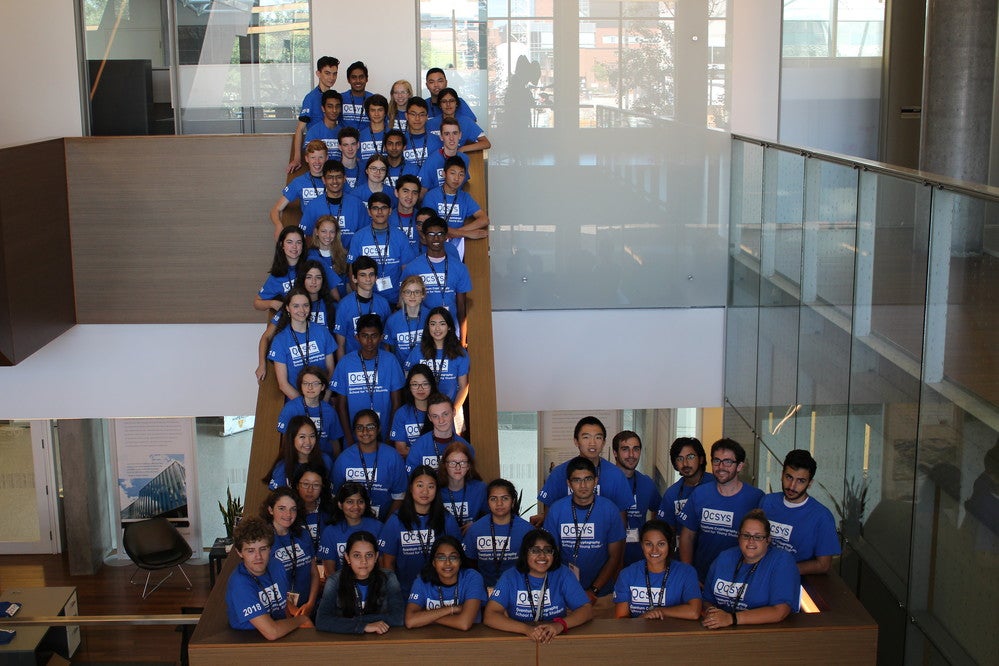 A group photo of past QSYS students on the IQC floating staircase