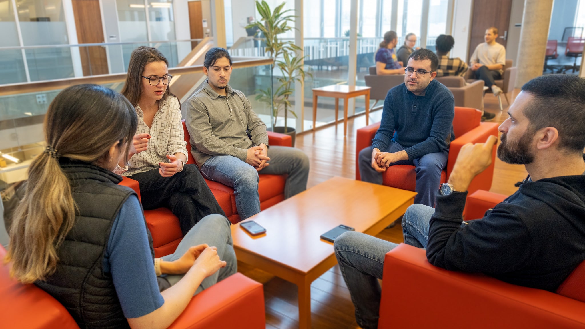 A group of five people sitting in red chairs