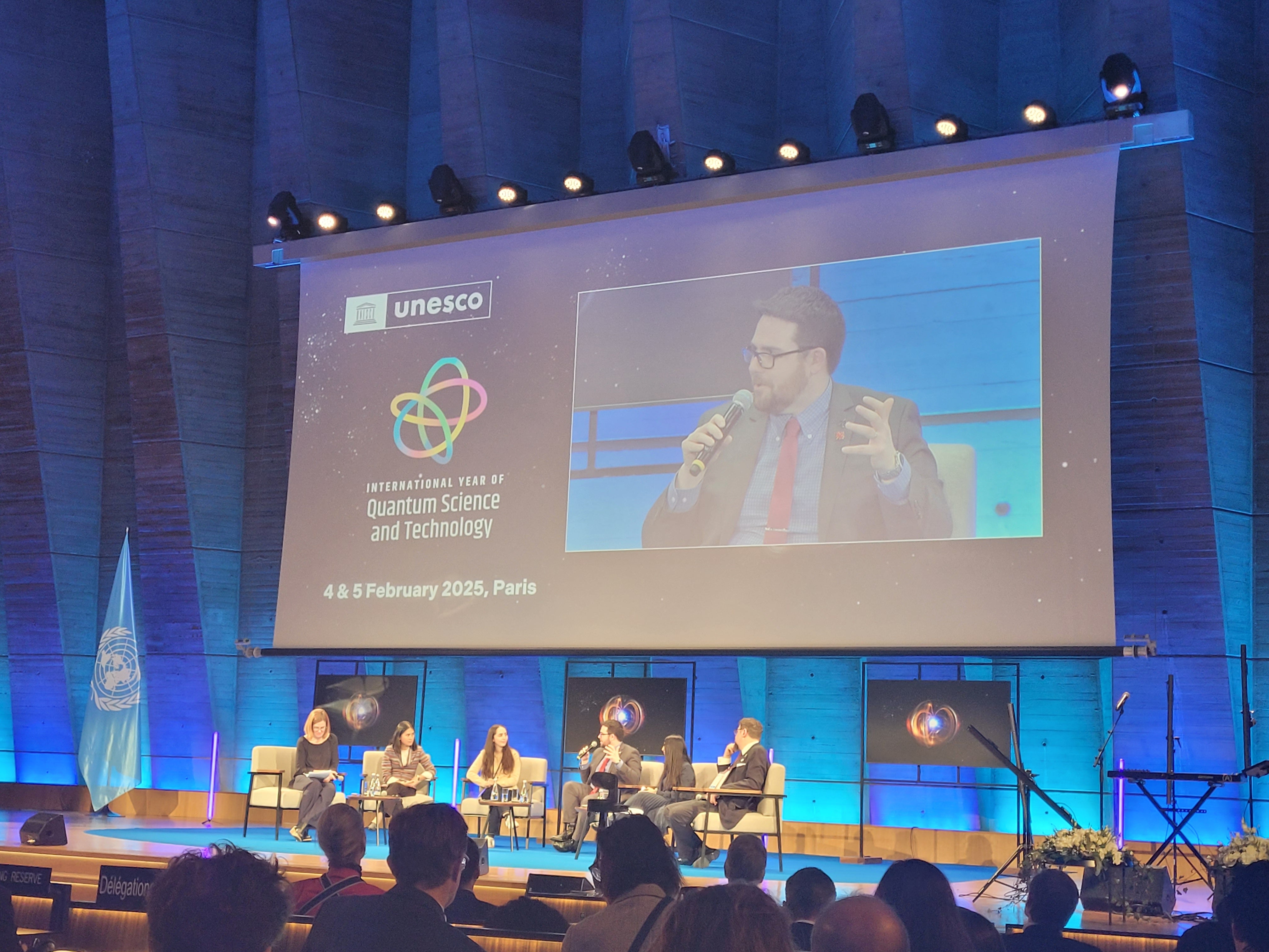 A panel with four people talking in front of a crowd with a projected image of John Donohue in the background