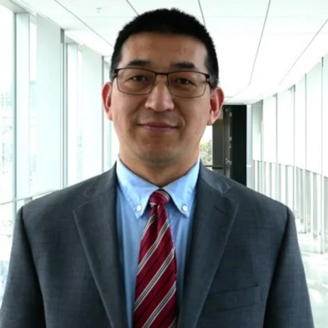 Dr. Boxin Zhao in a grey suit, blue shirt, and red tie