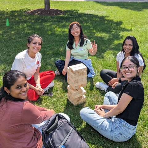 Five students sitting on the ground playing jenga