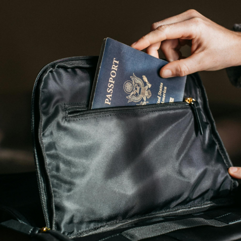 A hand taking a passport out of a black bag