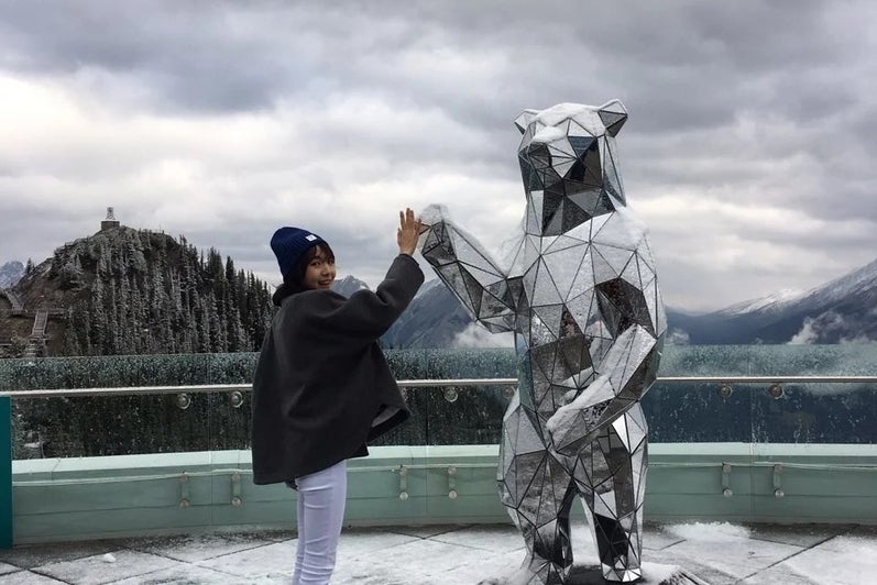 Si Yon high fiving the mirror bear statue in Banff, Alberta.