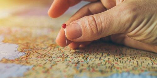 Person holding pin on map