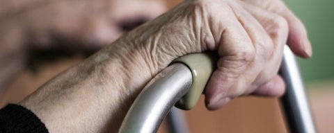 Older person's hand gripping a walker.