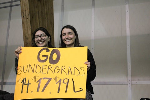 Spectators holding a "go undergrads" sign