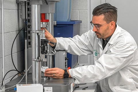 Nik Knowles wearing lab coat and using machine to analyze orthopaedic sample in lab.