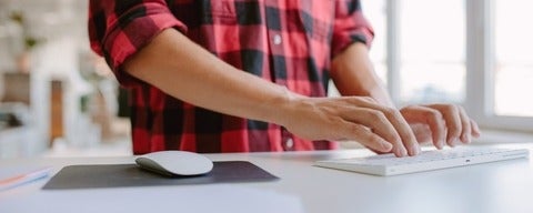 Man in plaid shirt typing while standing
