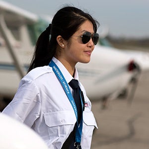 Student pilot wearing aviator sunglasses surveys runway.
