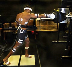 Brendan with sensors attached to his body while he punches a punching bag.