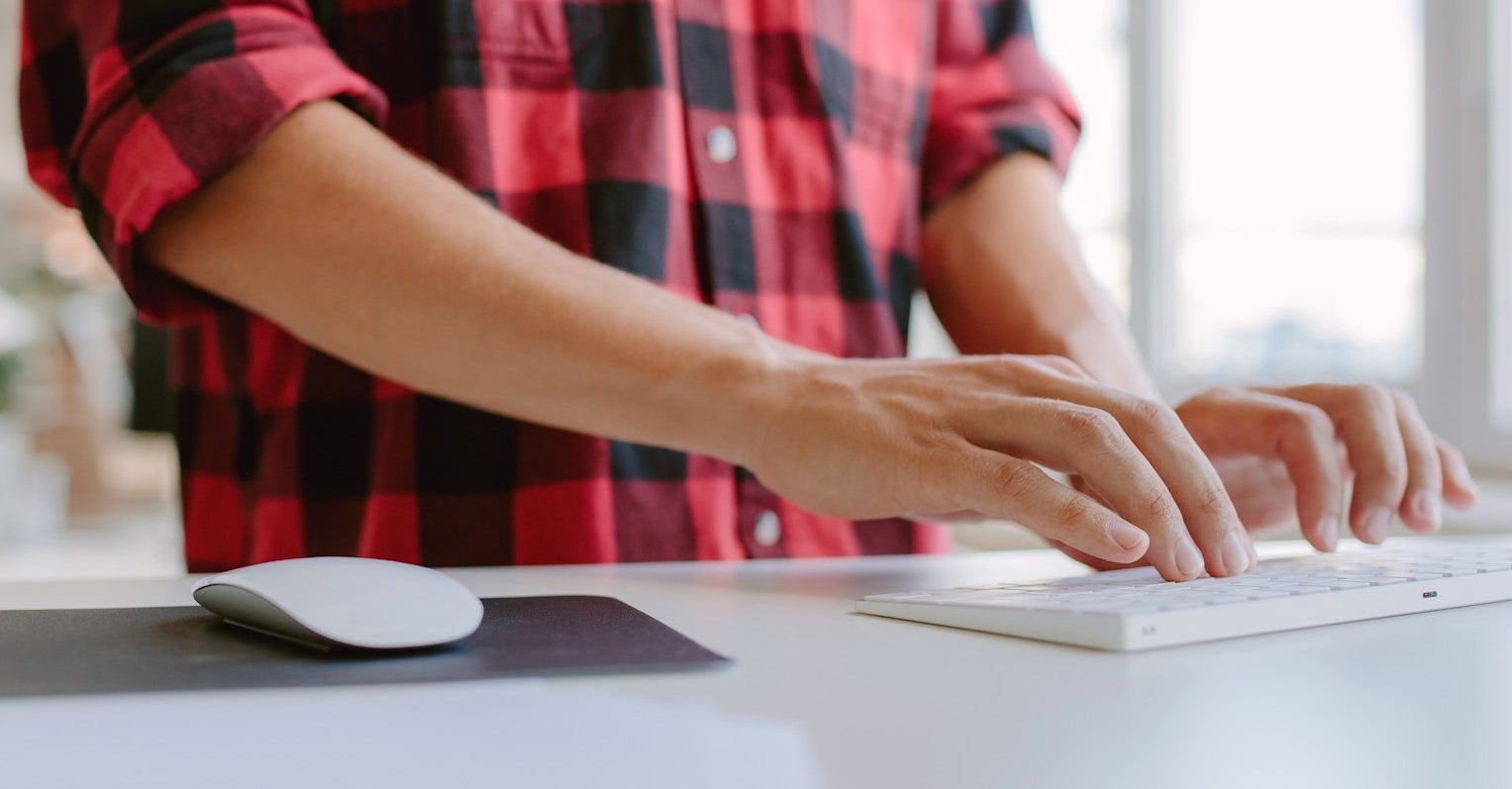 Person standing using a keyboard at a standing desk