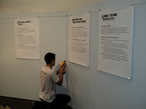 Student drilling into the exhibit wall.