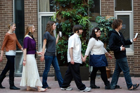 Six students walk towards the right in a line parodying the Abbey Road album cover by the Beatles.