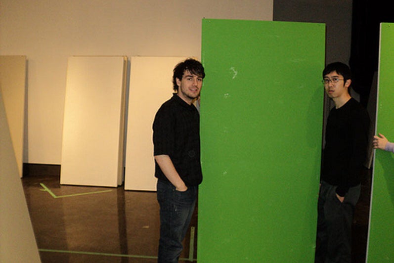 Students stand on either side of a green panel.