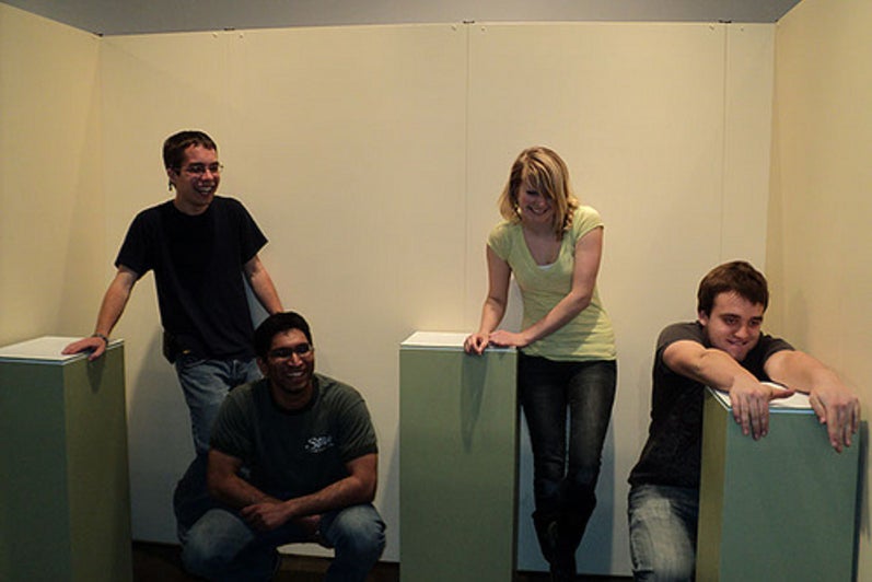 Four students pose around three green mid-height podiums.