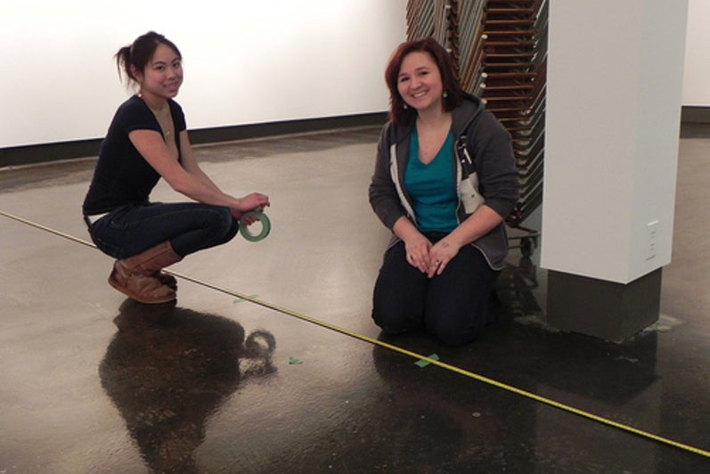 Kathy and Christina crouched on the floor over an extended measuring tape.