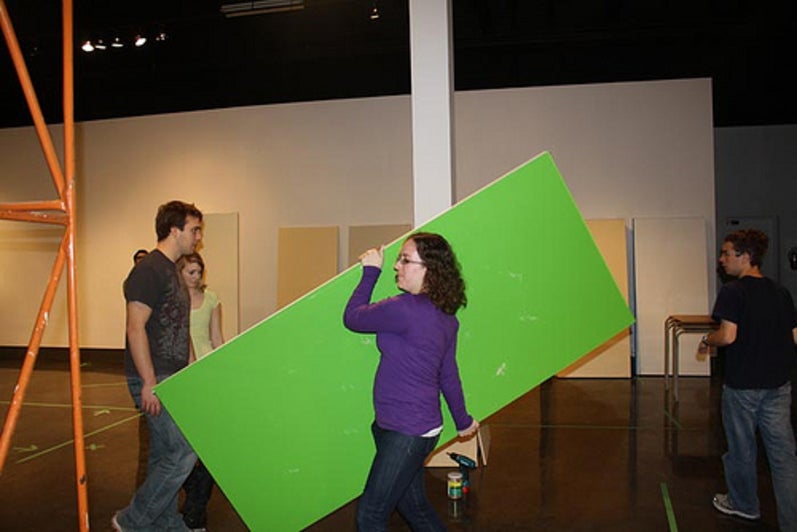 Student carrying large green door.