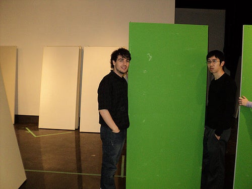 Students stand on either side of a green panel.