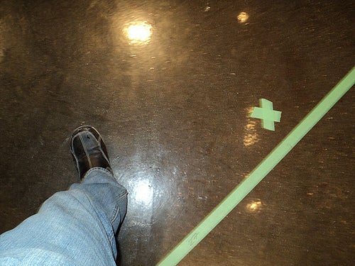Foot stepping over line of tape stuck to floor.
