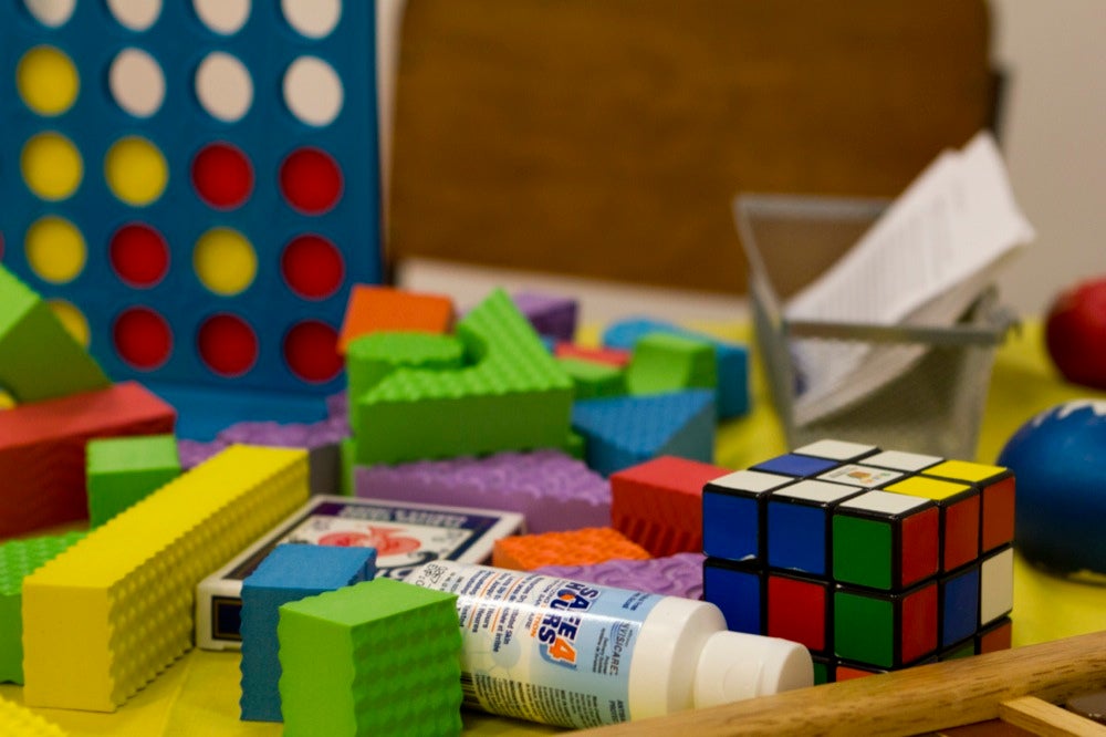 Close up of a Rubik's cube, playing cards, foam building blocks, and other toys.
