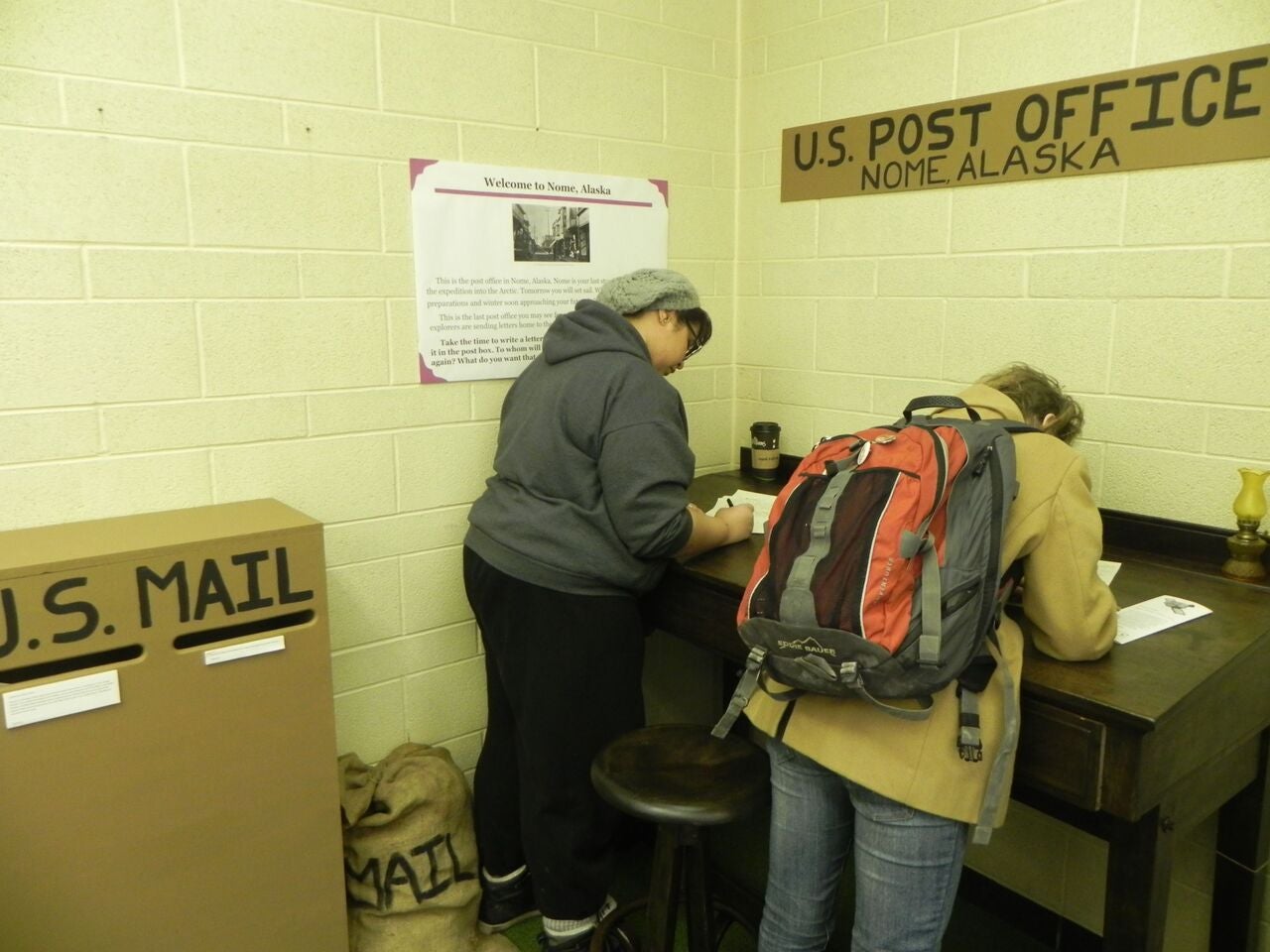 Two people at the exhibit in the "U.S. Post office"