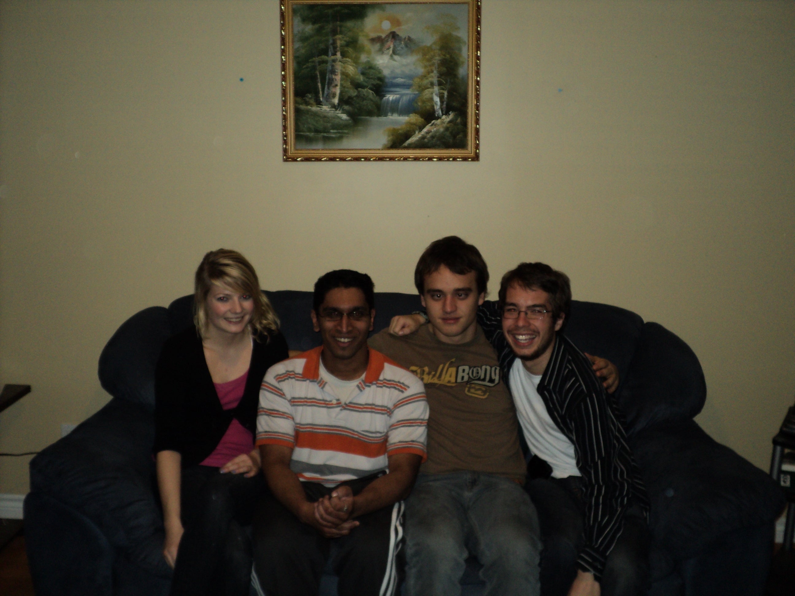 Laura Bell, Sharath Sundar, Barrett Lafortune, and Eric Kennedy posing together on a couch under a painting. 