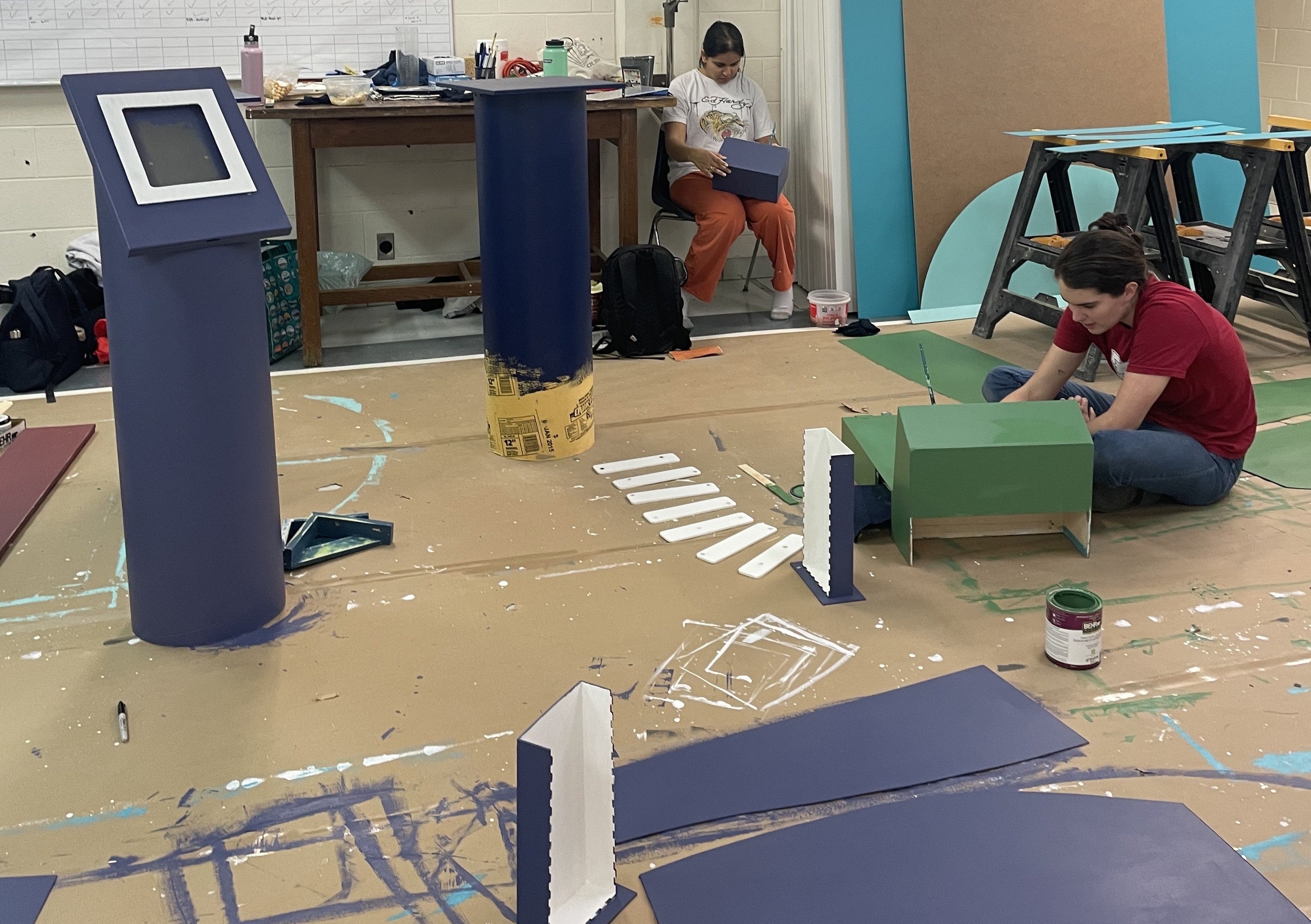 two people painting large pieces with green