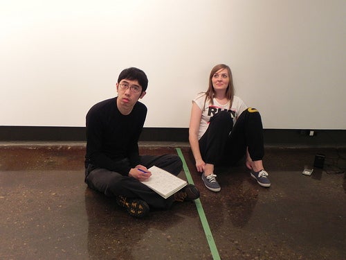 Keith and Liz sitting together on the floor of the gallery.