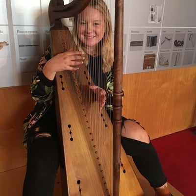 Student on harp at music museum