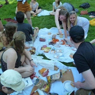 Students eating at a potluck picnic in the park