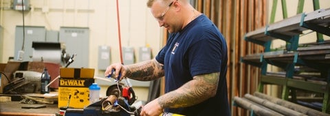 An employee soldering a pipe fitting.