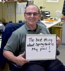 Benny Colussi holding a sign that says &quot;The best thing about spring term is my pool!&quot;