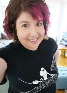 A selfie of Mary Lynne Bartlett wearing a shirt with an astronaut vacuuming up space. 