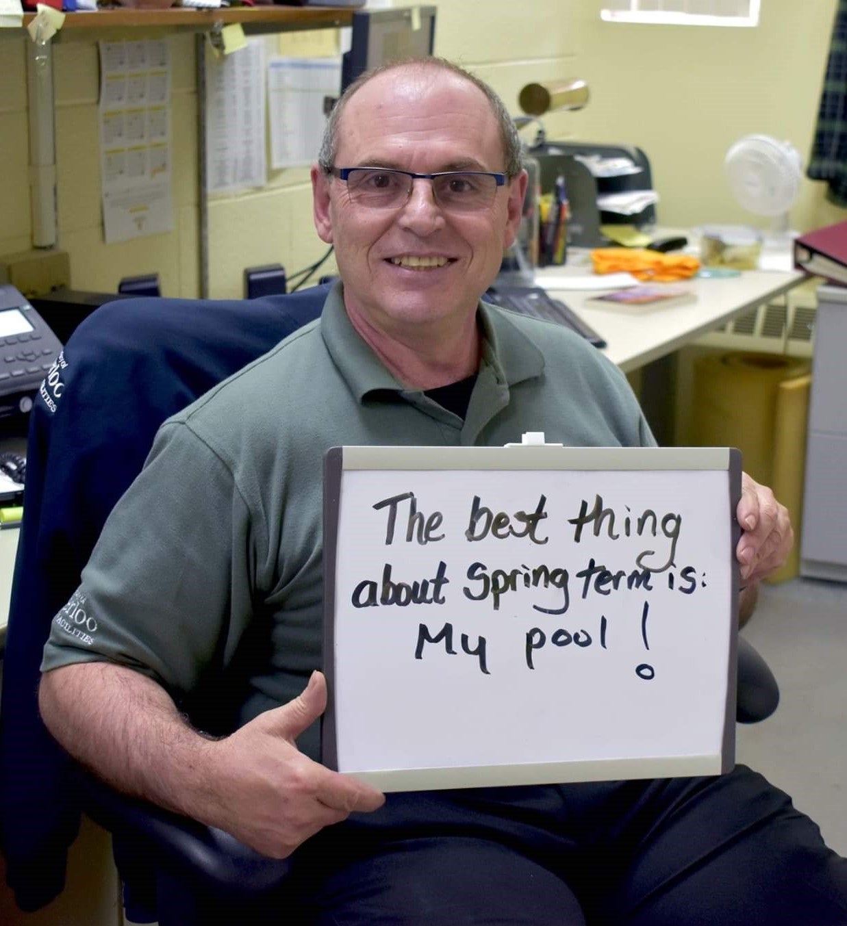 Benny Colussi holding a sign that says "The best thing about spring term is my pool!"