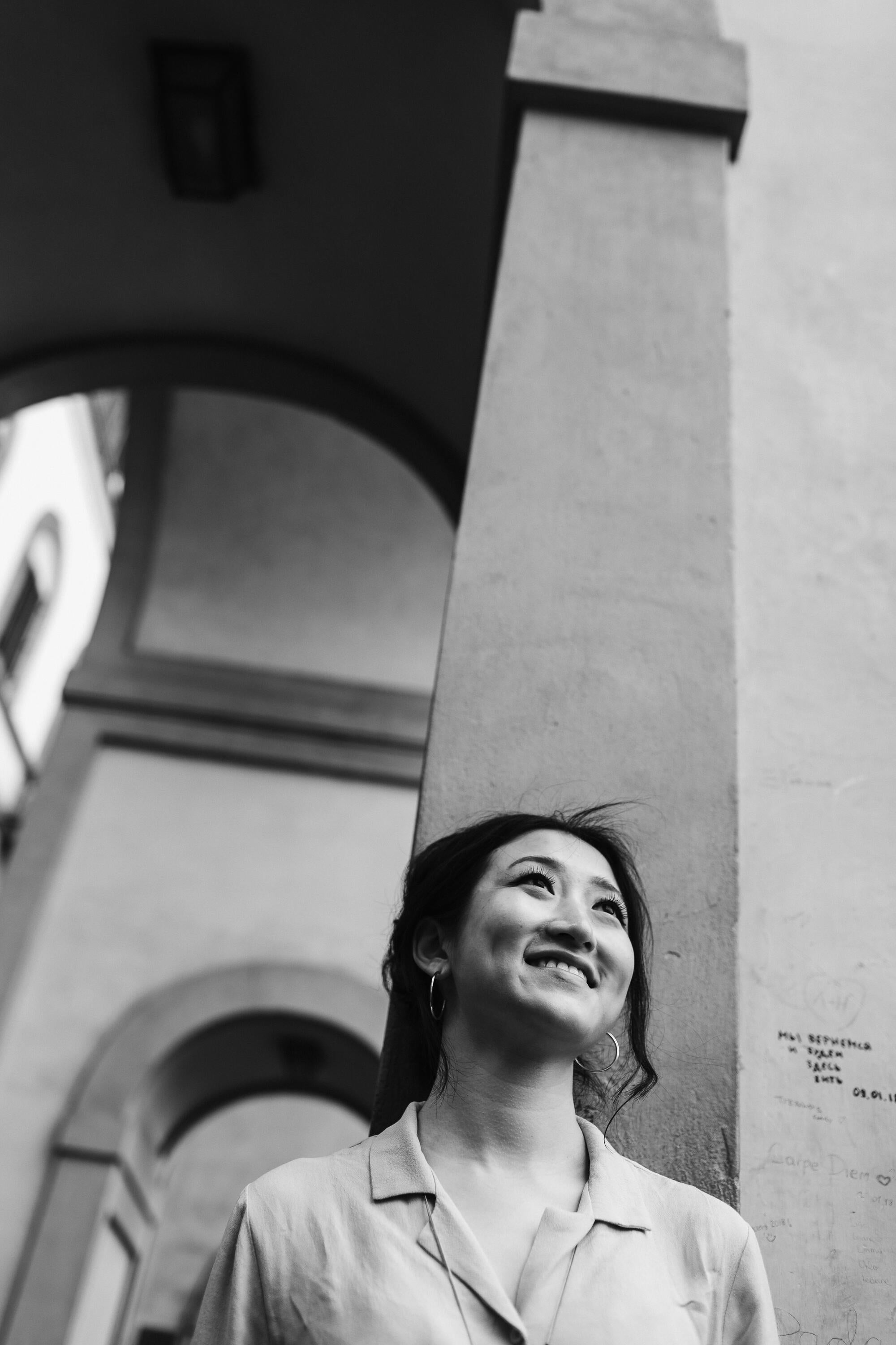 Eva Ma standing in front of a building archway. Black and white photo. 