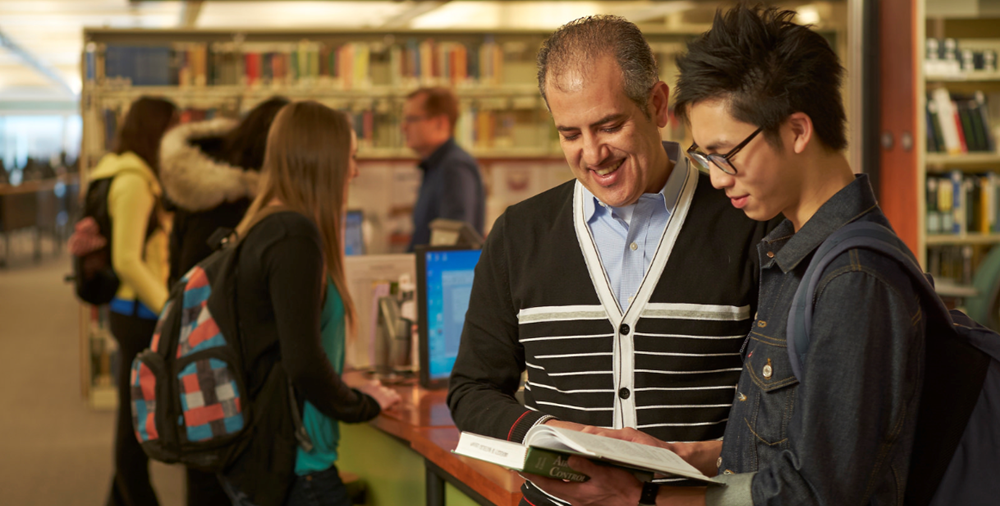 A staff member helps a patron at the Davis Centre library circulation desk.