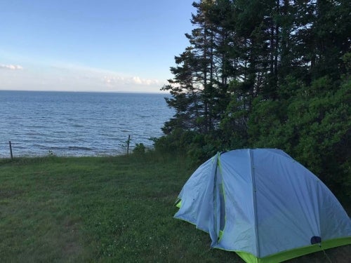 A tent set up on the shore of a large body of water.