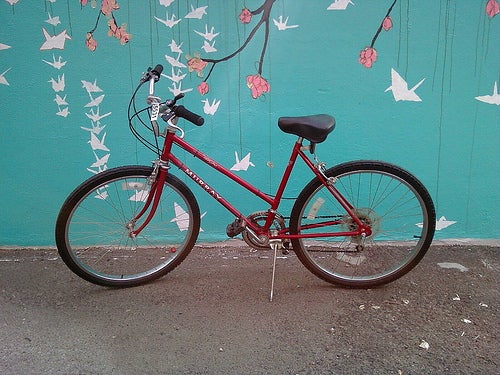 A red bicycle in front of a painted wall. 