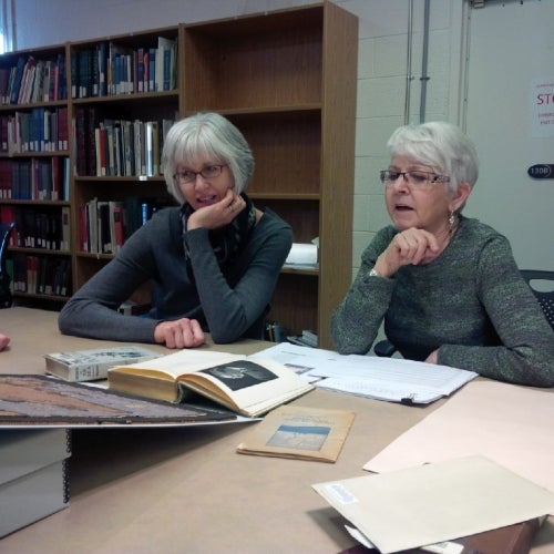 Two library staff members sitting around a desk.