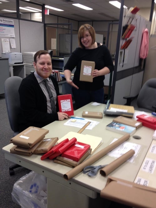 Mary Lynne and Patrick wrapping books in red paper.