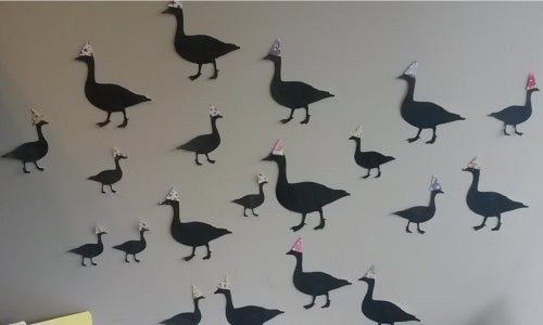 Silhouettes of geese wearing colourful party hats.