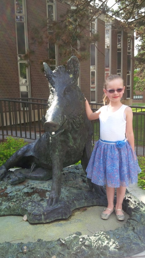 A young girl posing with the Porcino statue.