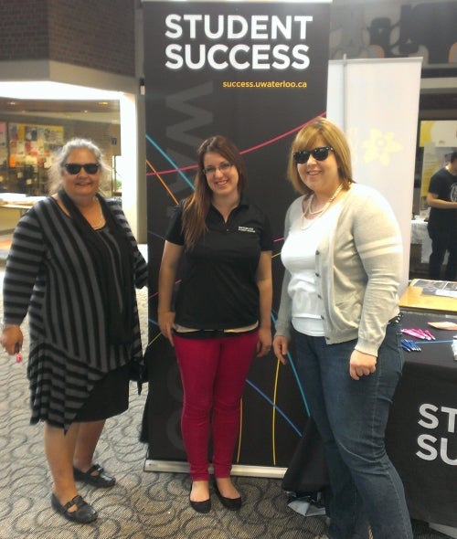 Staff wearing sunglasses and standing in front of the Student Success banner