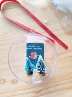 clear ornament with trees and ribbon on table